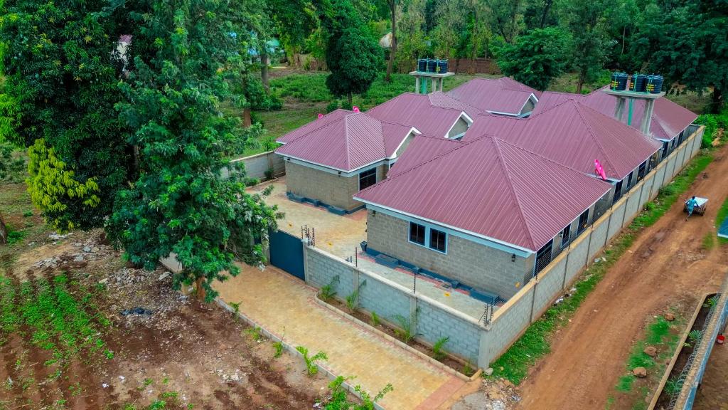 Aerial view of Jasy Retreat's red-roofed cottages surrounded by green trees in Moshi